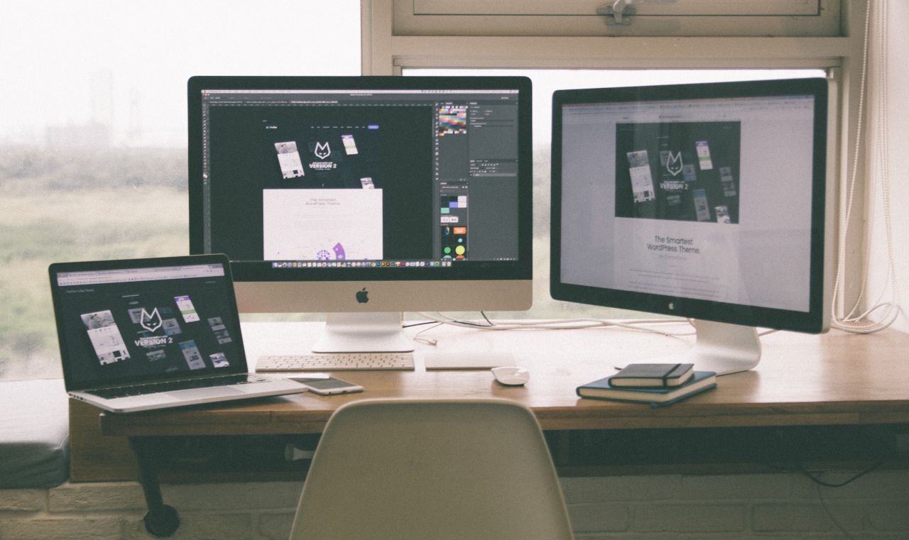 Un espacio de trabajo moderno y eficiente con varios monitores, un portátil y un smartphone, mostrando un proyecto de diseño web.