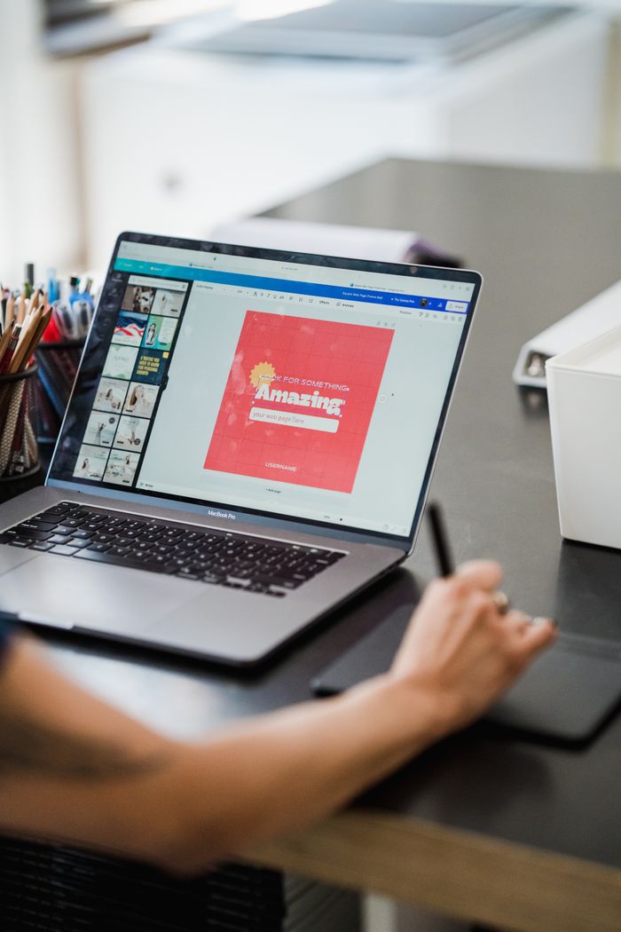 Persona que usa una laptop y una tableta gráfica para realizar trabajo de diseño digital en una oficina en casa.
